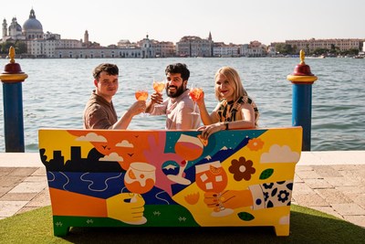 Three artists pose with their collaborative piece of urban art, a sofa celebrating Aperol's centenary and role in sparking joyful connections (PRNewsfoto/Aperol)