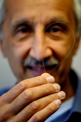 Colin Baker, U.S. Naval Research Laboratory, holds a silica glass rod (optical preform) that will be pulled into an optical fiber suitable for production of an eye safer laser at U.S. NRL, DC on March 26, 2019. (U.S. Navy photo by Jonathan Steffen)