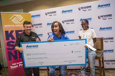14-year-old Serenity Gary and her grandmother, 58-year-old Karlette “Koko” Karras, receive a surprise $15,000 check from Mike Dickerson, VP of Corporate Communications & Investor Relations at Aaron’s, Inc., at the Boys & Girls Clubs of America’s 52nd National Keystone Conference presented by Aaron’s, Inc.. The donation is for her charity Serenity’s Grace, which fights homelessness and hunger in the Orlando area. (Roberto Gonzalez/AP Images for BGCA).