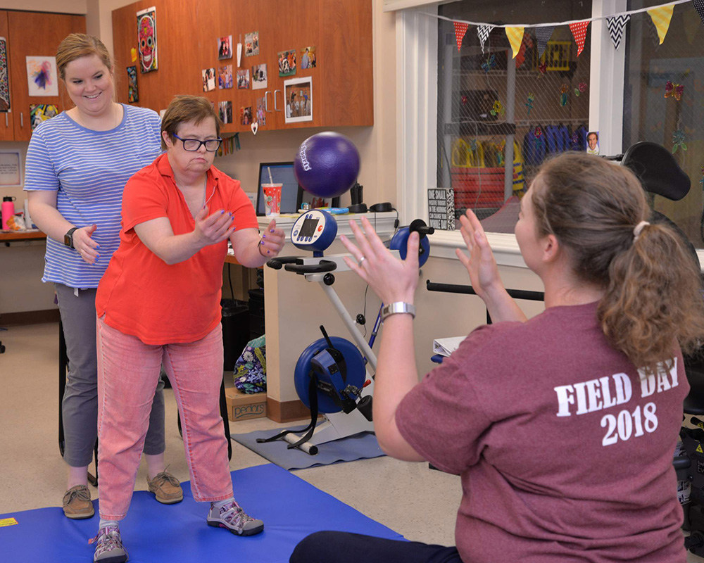 Members of Melmark's Rehabilitative Services Team working with an individual in the existing Physical Therapy space