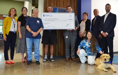 PenFed Credit Union employees and Journey, PenFed's Northwest Battle Buddies service-dog-in-training, present a donation check to Lane County Stand Down, an annual event that provides one-stop services for veterans